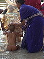 वाराणसी के घाट पर बच्चे को स्नान कराती महिला